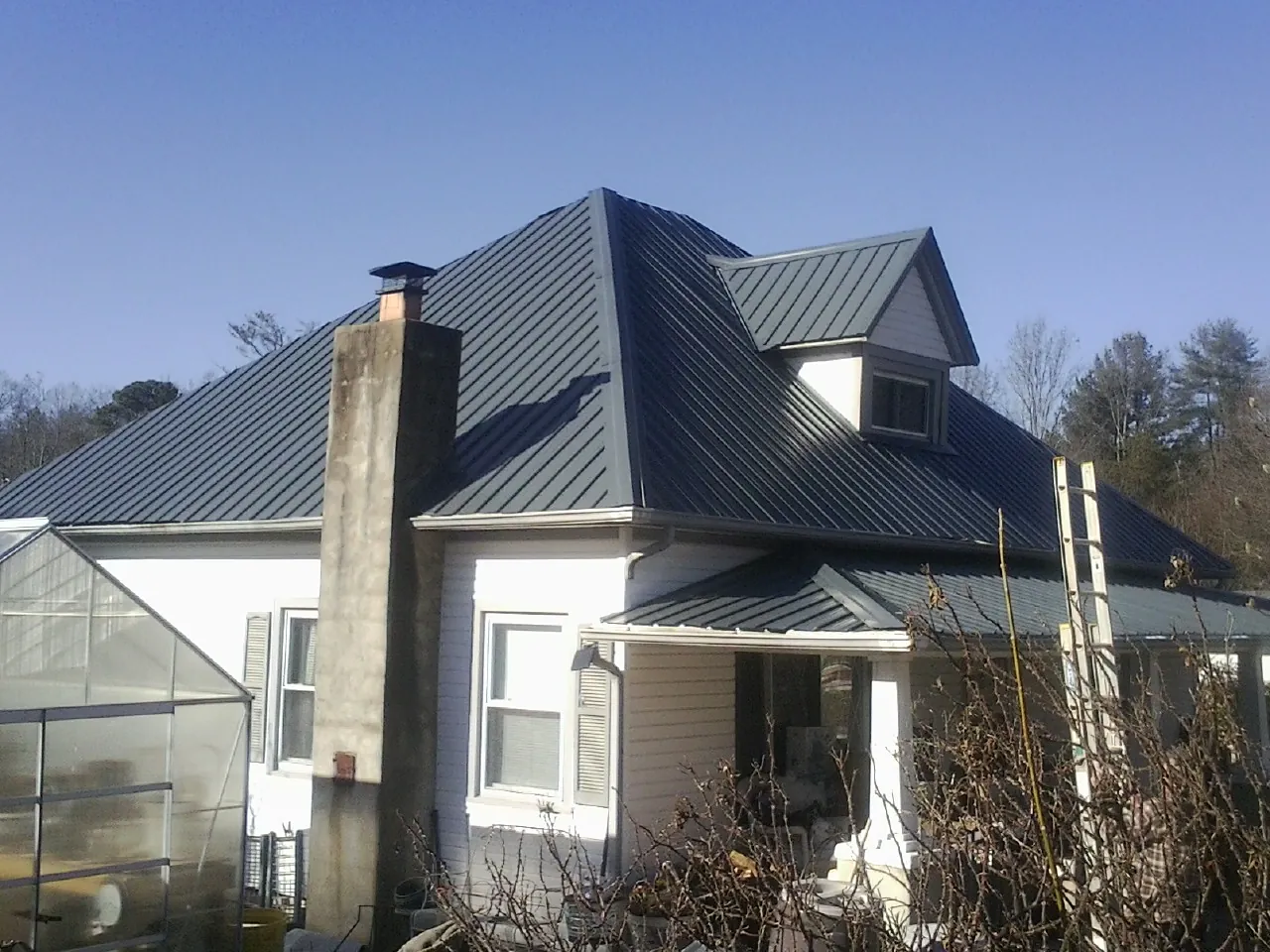 Dark blue standing seam metal roof on a white farmhouse with dormer — Slate & Tile Roof Repair by Roofing Brothers in Wheaton