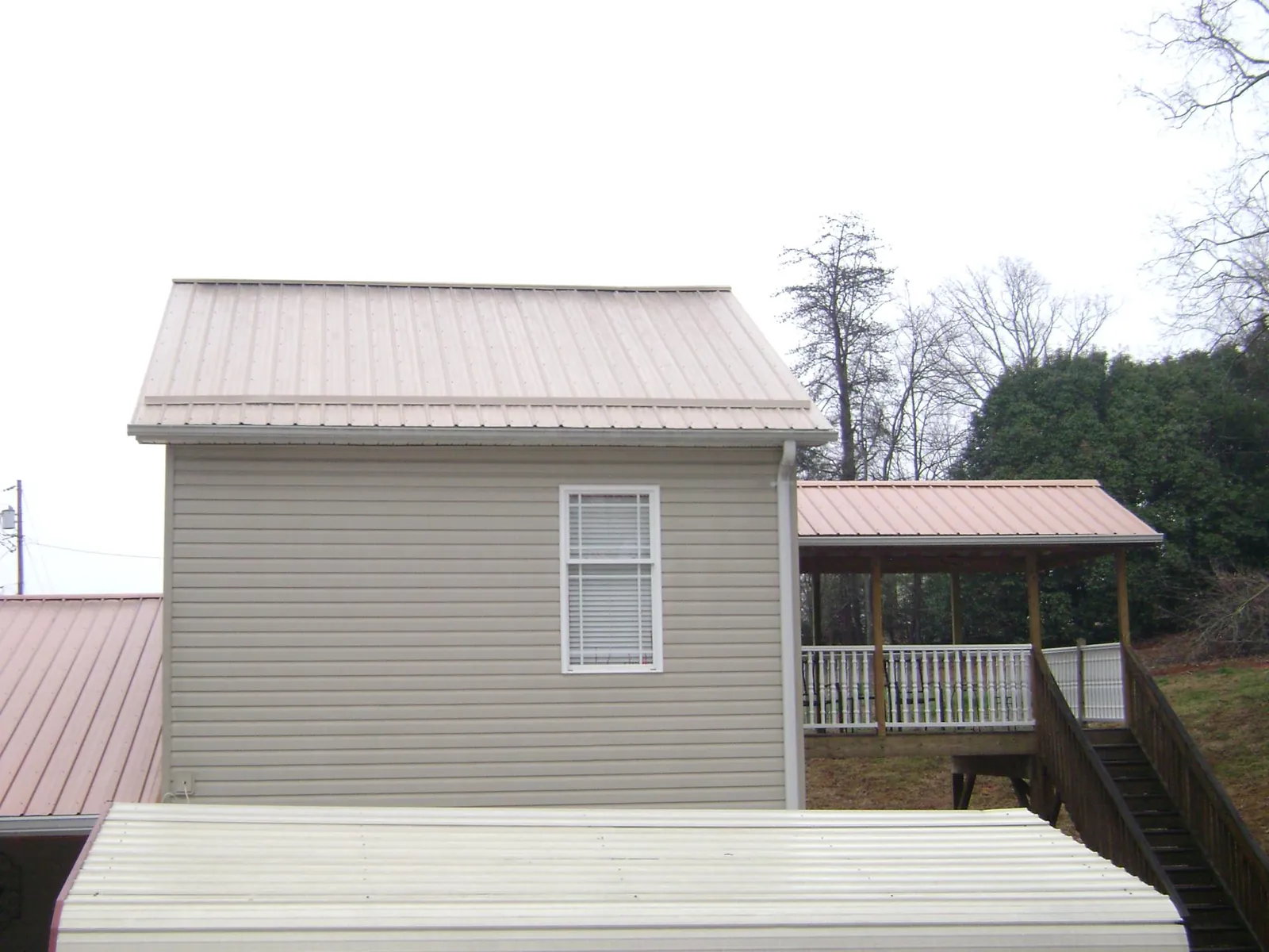 Tan metal roofs on a two story addition and attached porch, from a Roof Replacement job in Wheaton